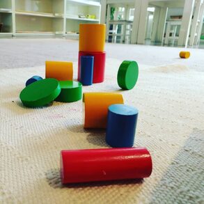 Circular wooded blocks painted red, green, blue, and yellow on a carpet