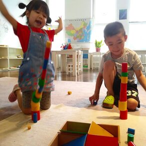 Children getting excited over falling blocks at a Montessori school